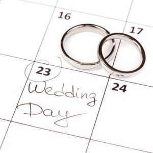 Two simple wedding bands sit on top of a calendar above a box labeled ‘wedding day’