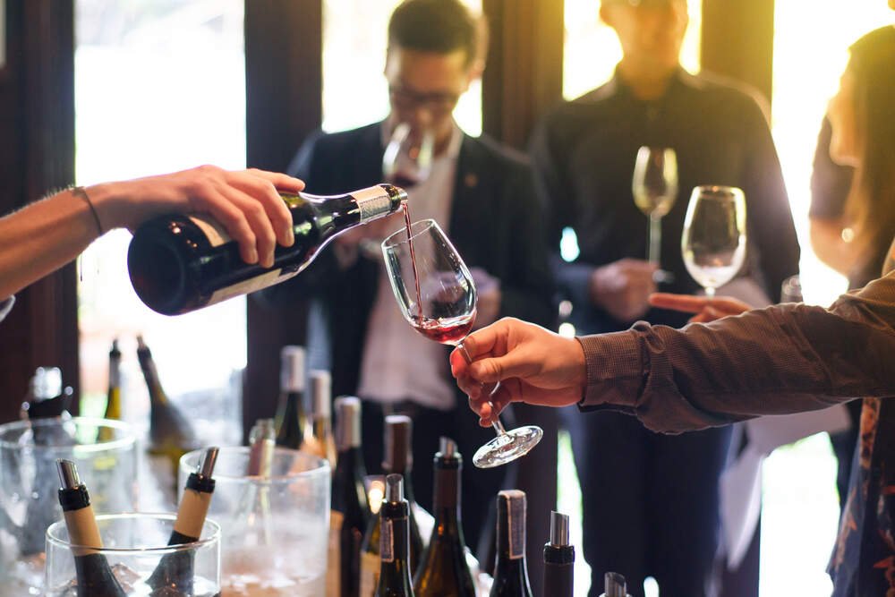 Someone pours a glass of wine at a corporate event